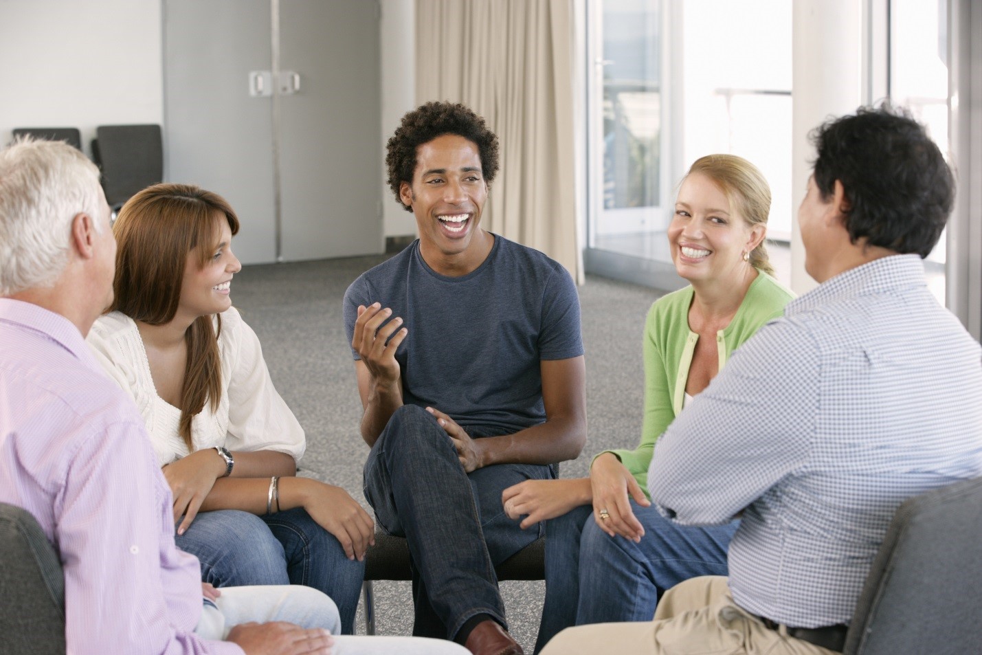 Smiling people sitting around in a circle talking