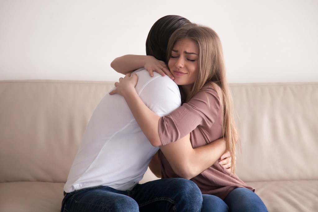 Young man and woman hugging each other on the couch