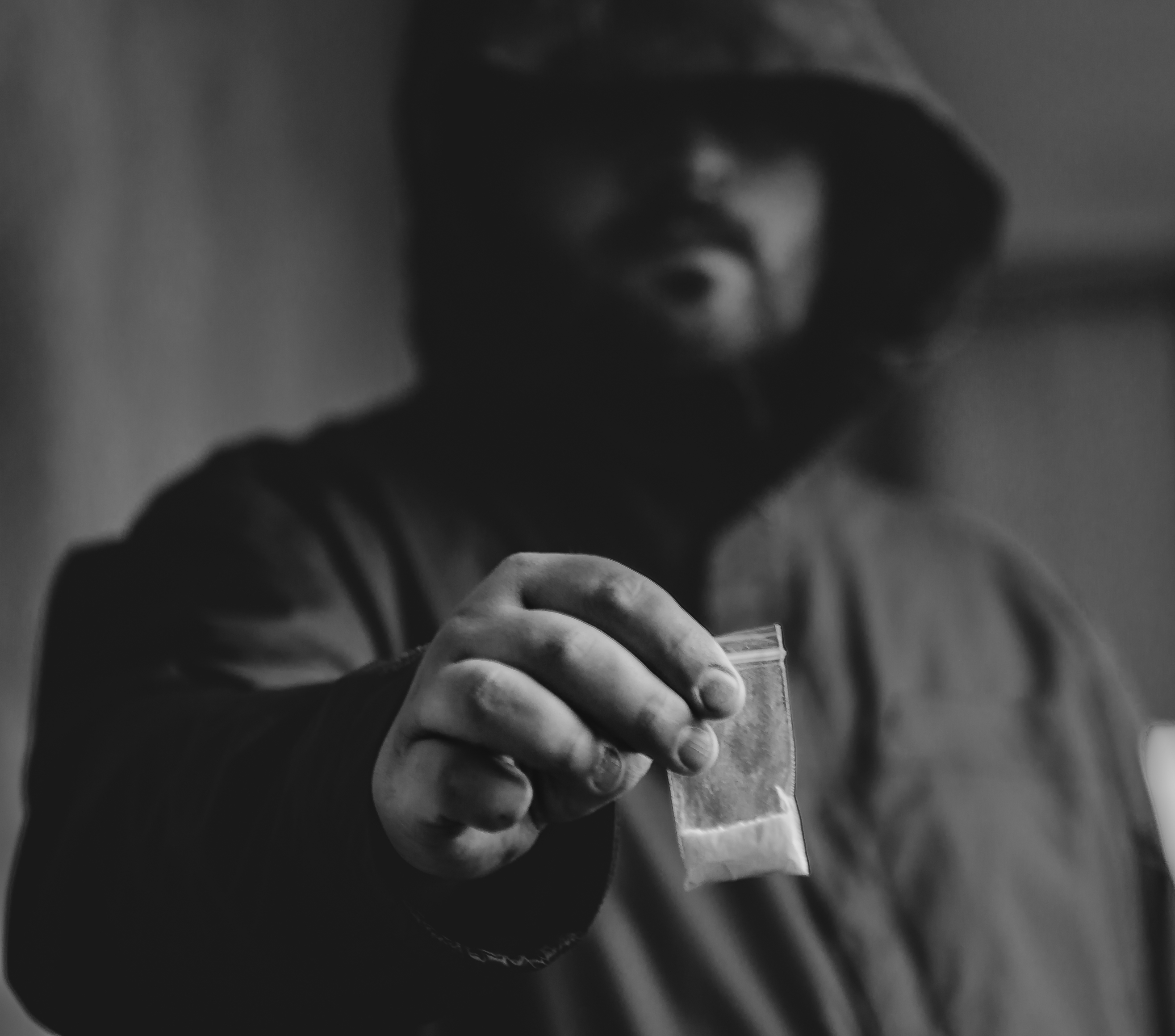 Drug dealer selling drugs junkie. Drug abuse concept and overdose concept. Mans hand holds plastic packet with cocaine powder, selective focus, black and white photo
