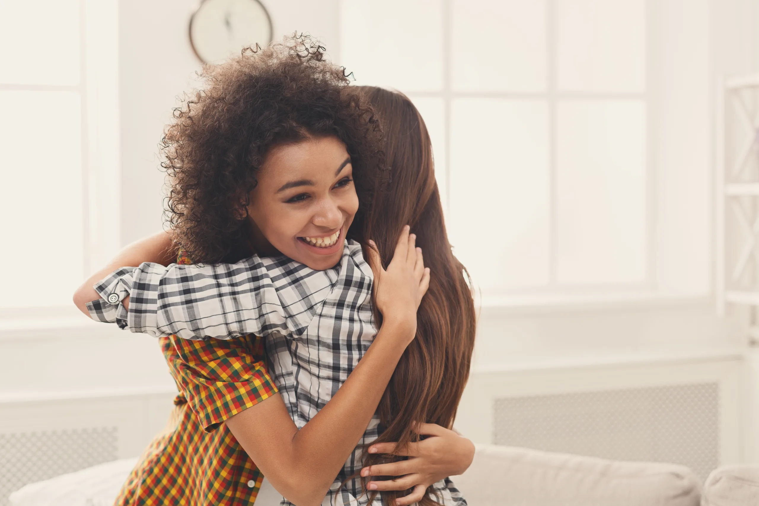Two female friends embracing each other at home. Happy women hugging, success, unity and togetherness concept, copy space