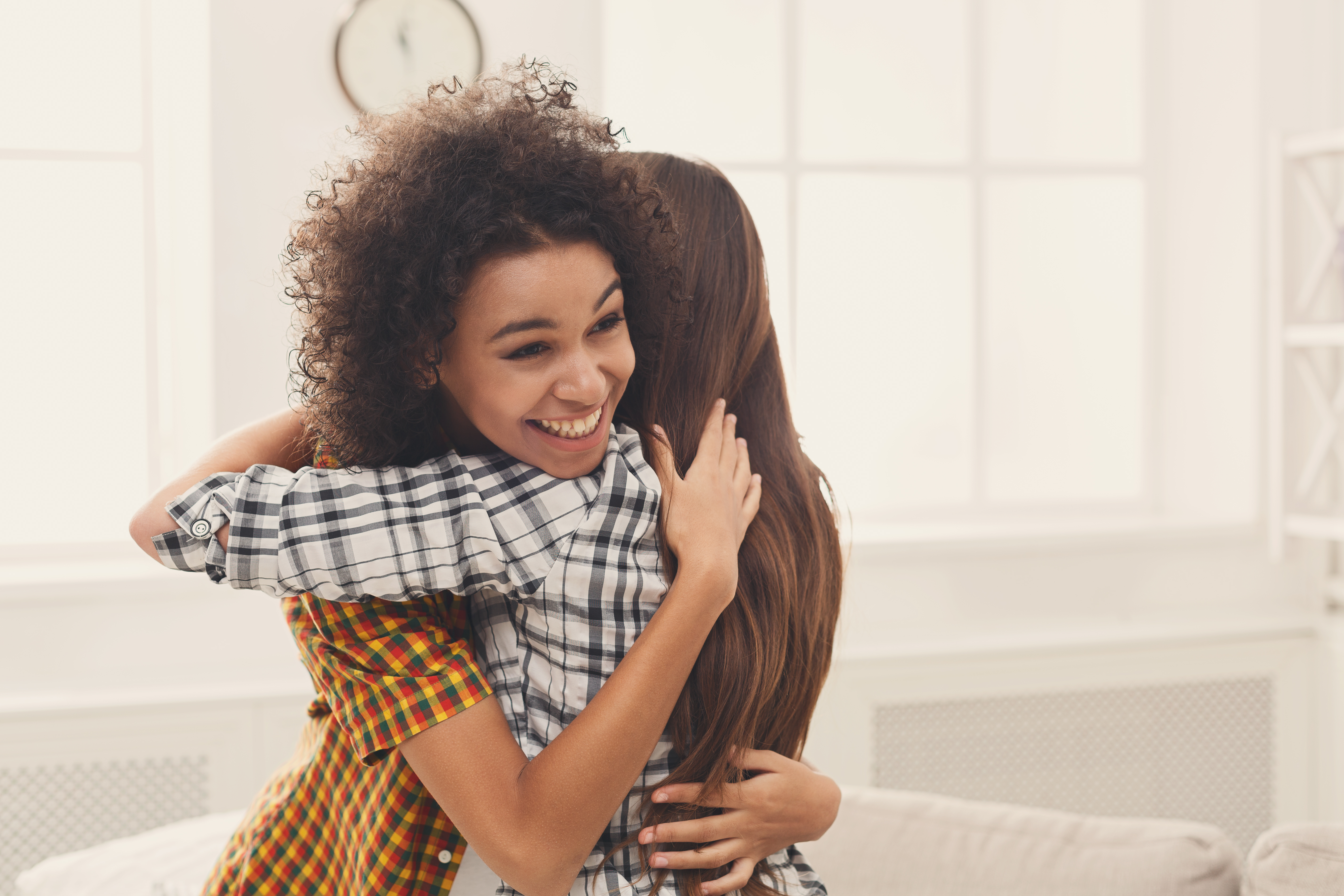 Two female friends embracing each other at home. Happy women hugging, success, unity and togetherness concept, copy space