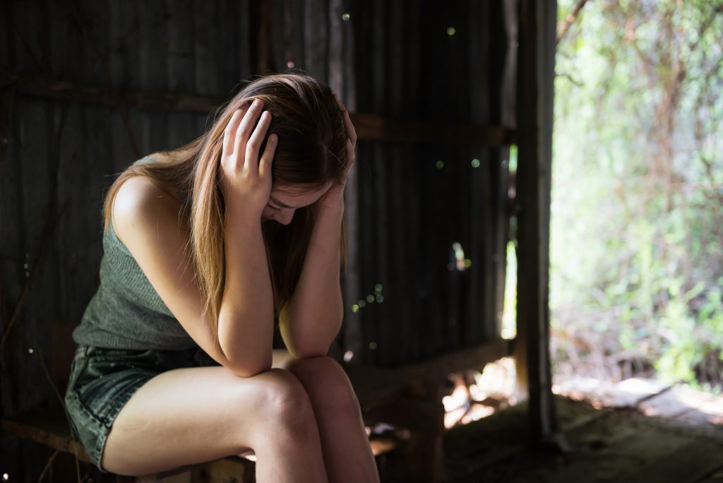 Social issue of Stress, depress, headache, addiction concept. Young Asian woman hands touching her head in abandoned house at rural forest.