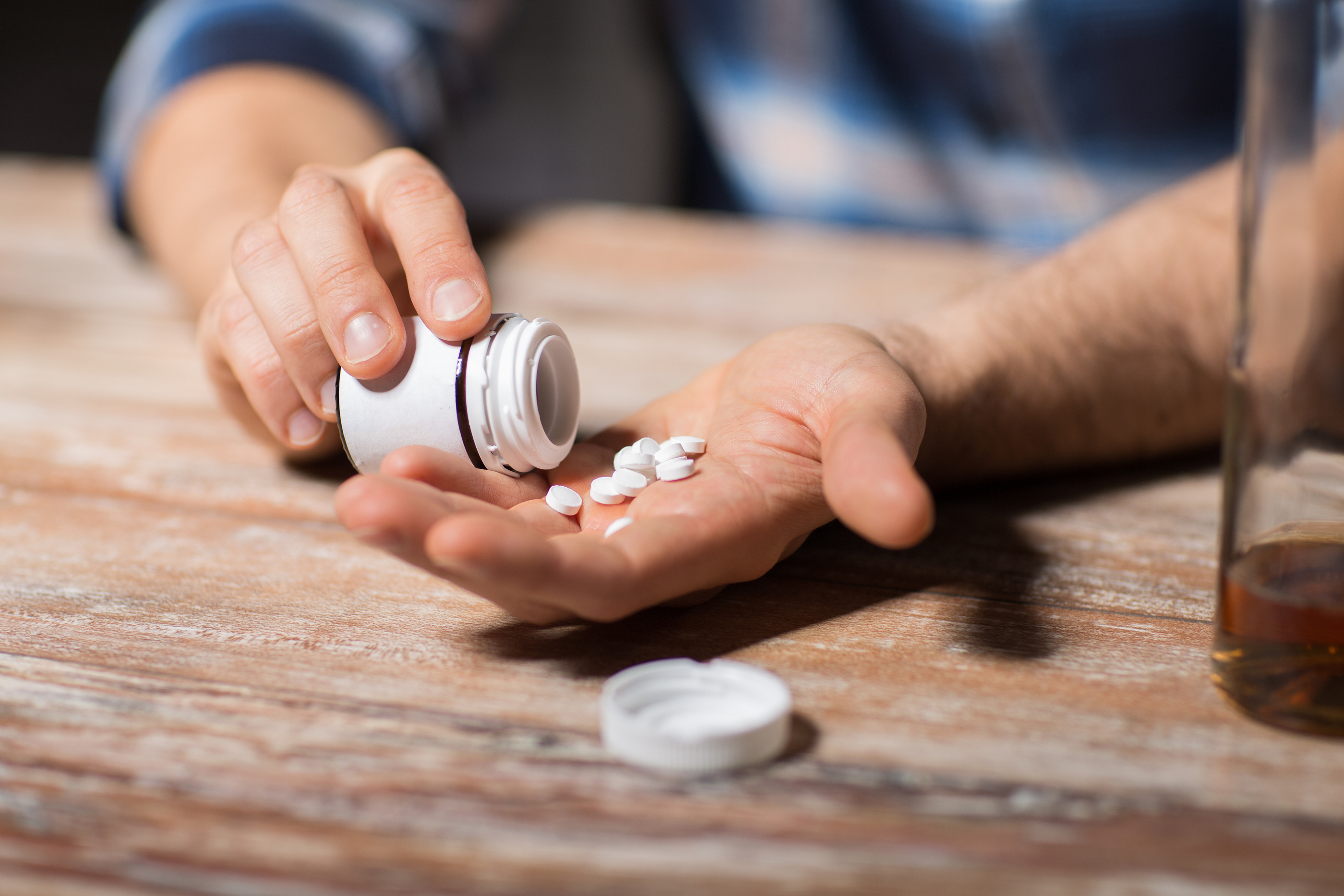 depression, drug abuse and addiction people concept – unhappy dr depression, drug abuse and addiction people concept - unhappy drunk man with bottle of alcohol and pills committing suicide by overdosing on medication at night