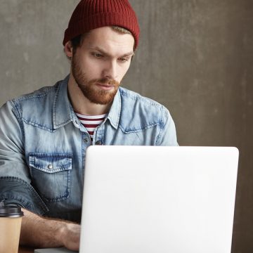 Man wearing beanie staring intently at his laptop