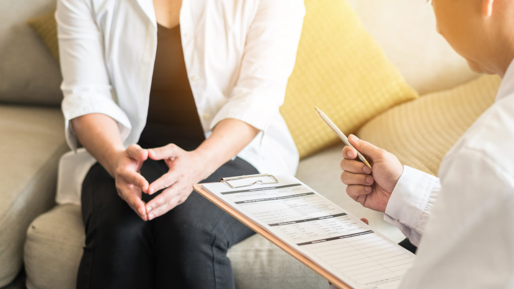 Doctor (gynecologist or psychiatrist) consulting and examining woman patient's health in medical clinic or hospital health service center