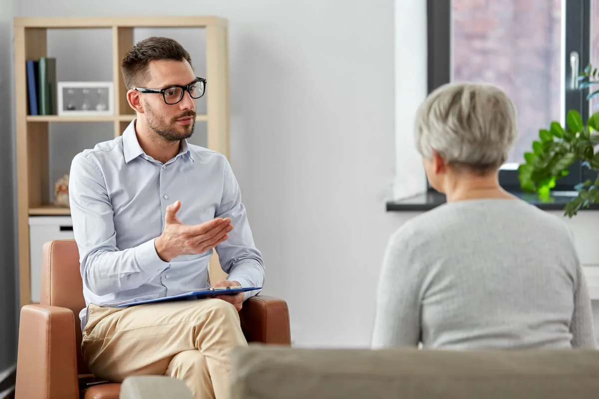 A mental health therapist discusses cognitive defusion with their patient in a clinical setting.
