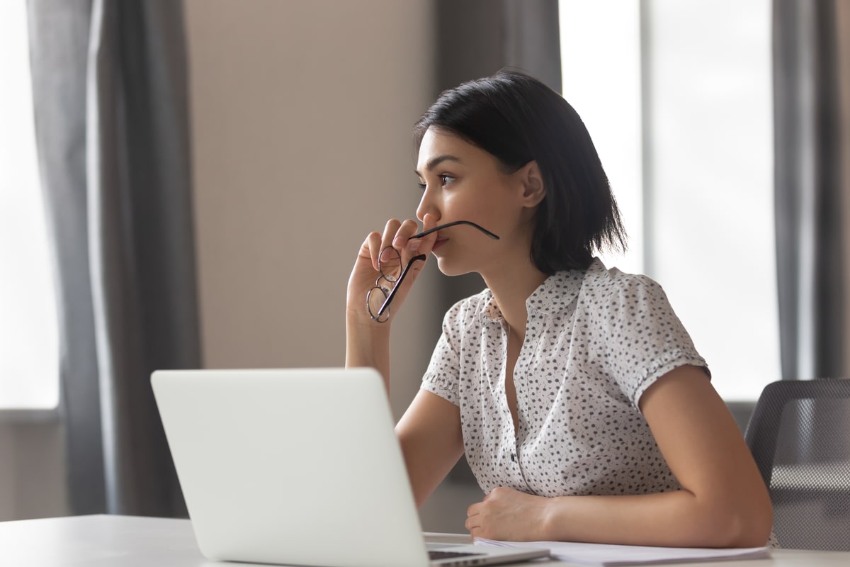 An anxious woman sits in front of her laptop while working from home during the COVID-19 pandemic