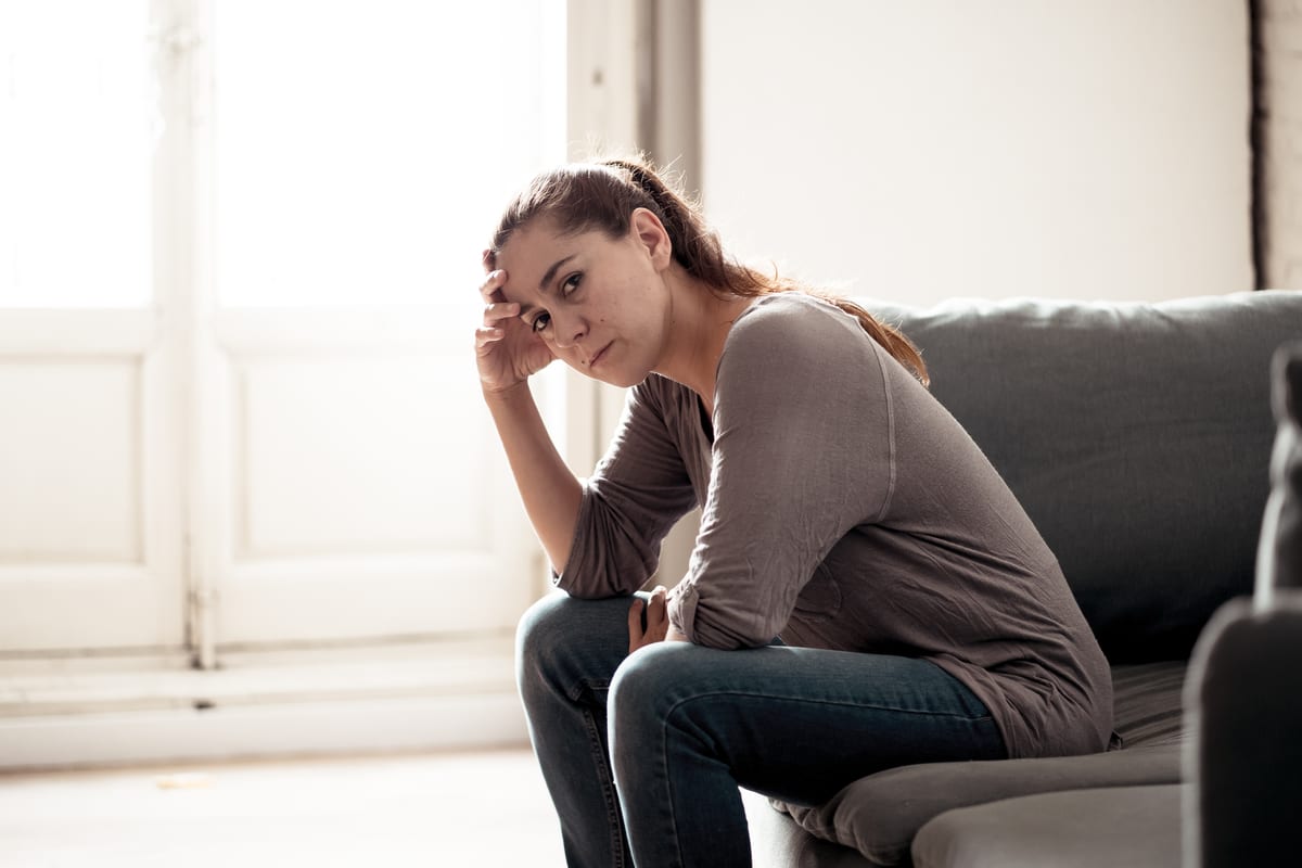 A woman suffering from PTSD sits at home, distressed