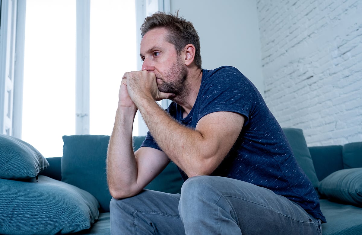 A young man sits in his apartment, distressed by his OCD compulsions.