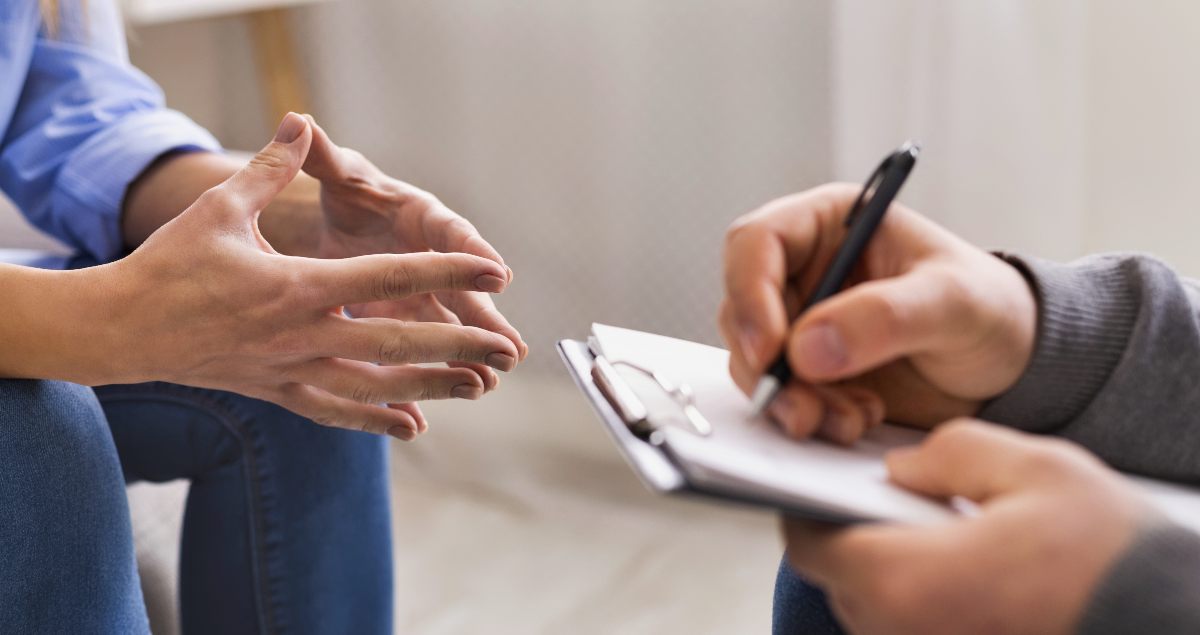 A therapist takes notes while listening to their patient describe the challenges they are experiencing in overcoming substance abuse