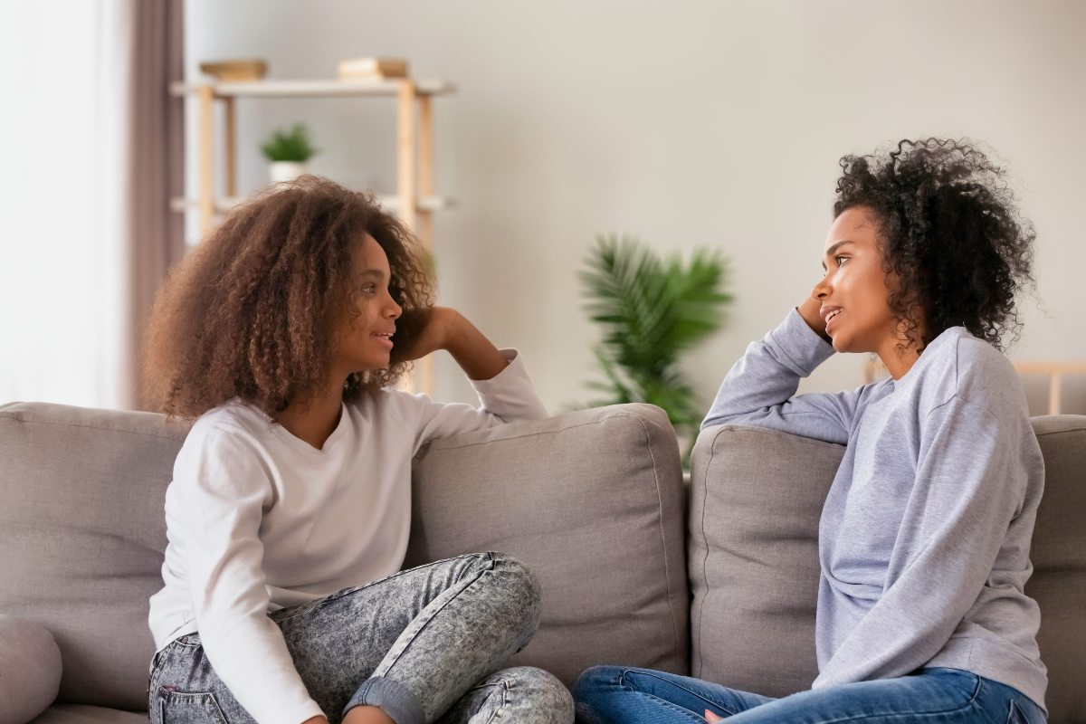 A mother sits across from her teen daughter as they talk about mental health and healthy coping skills