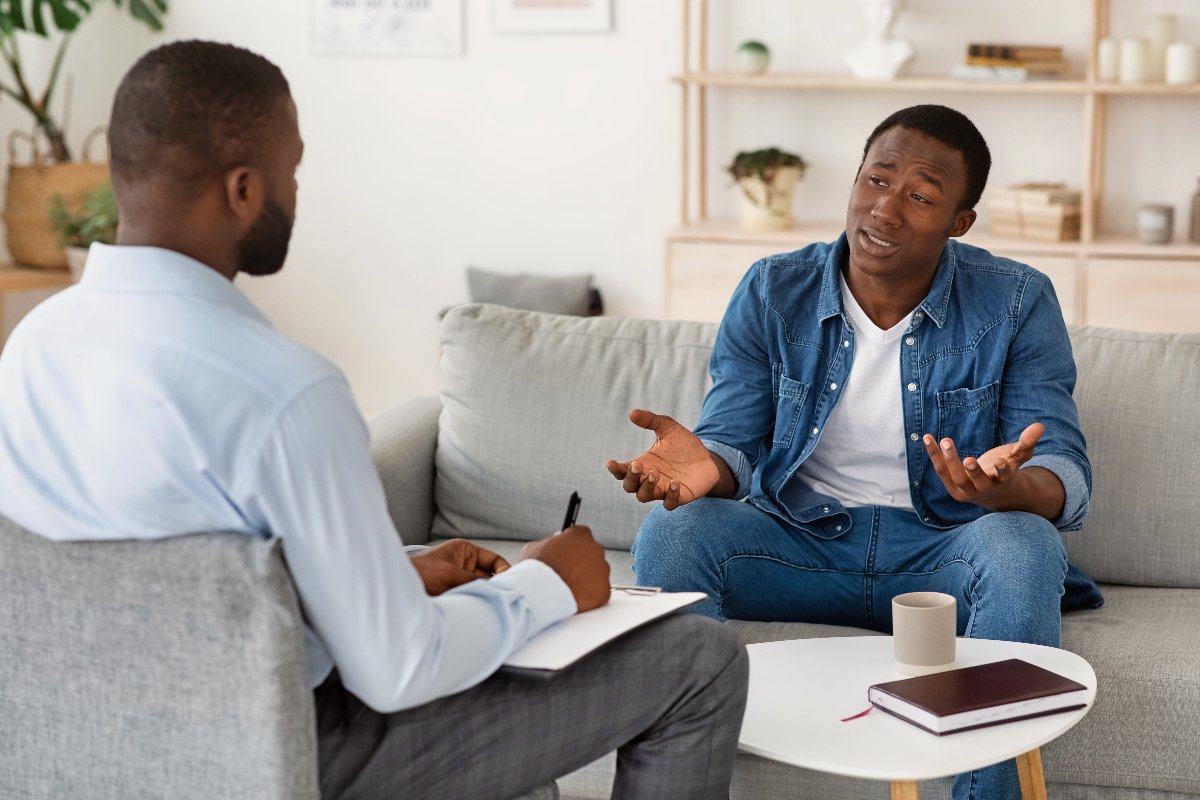 A young man sits across from a therapist and explains his current mental health condition