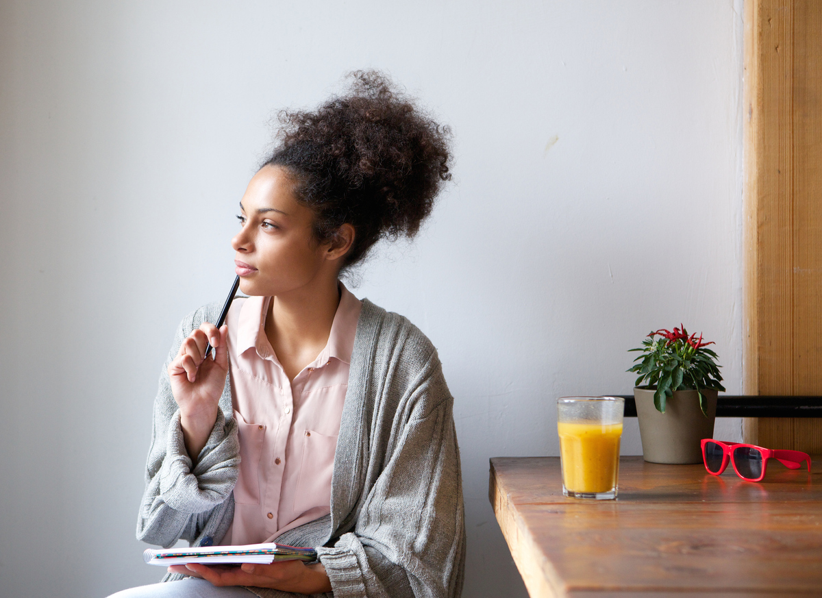 Young woman sitting at home with pen and paper