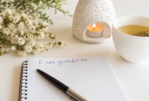close-up-of-handwritten-text-i-am-grateful-for-in-foreground-with-notebook-pen-cup-of-tea-flowers-and-oil-burner-in-soft-focus-deliberate-angle-stockpack-istock Close up of handwritten text "I am grateful for..." in foreground with notebook, pen, cup of tea, flowers and oil burner in soft focus (deliberate angle)