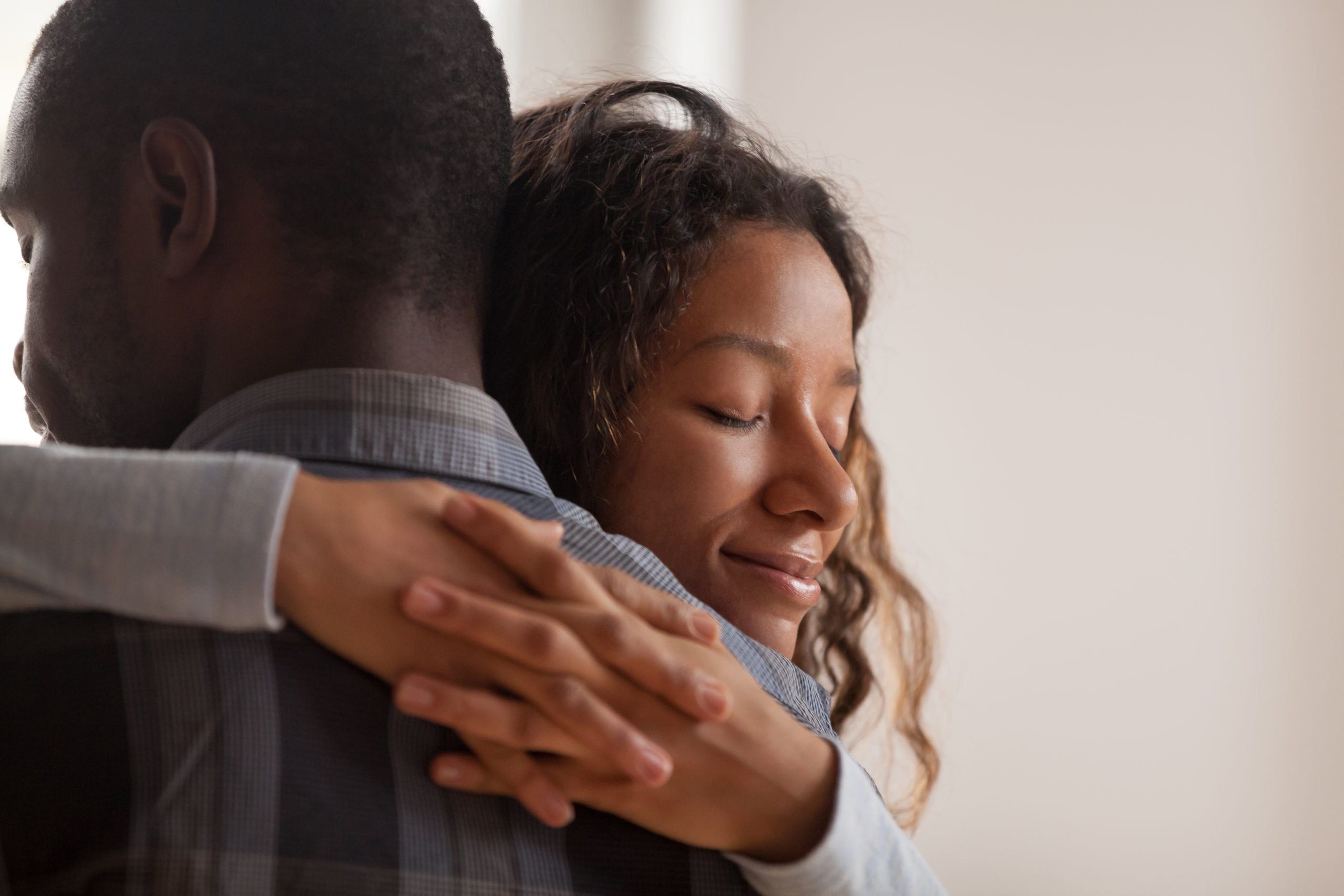 Close up young black american wife embracing husband. Portrait of woman with closed eyes, man rear view. Attractive affectionate couple in love, romantic relationship support and gratefulness concept