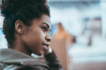 close-up-side-view-of-a-young-cute-brazilian-girl-with-a-curly-afro-hair-and-in-a-dark-green-light-overcoat-looking-aside-with-defocused-background-and-copy-space-place-for-your-text-or-advertising-stockpack-istock