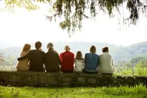 rear-view-of-multi-generation-family-relaxing-in-row-on-retaining-wall-against-clear-sky-stockpack-gettyimages