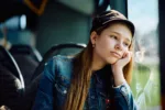 Pensive little girl feeling bored while traveling by public bus.