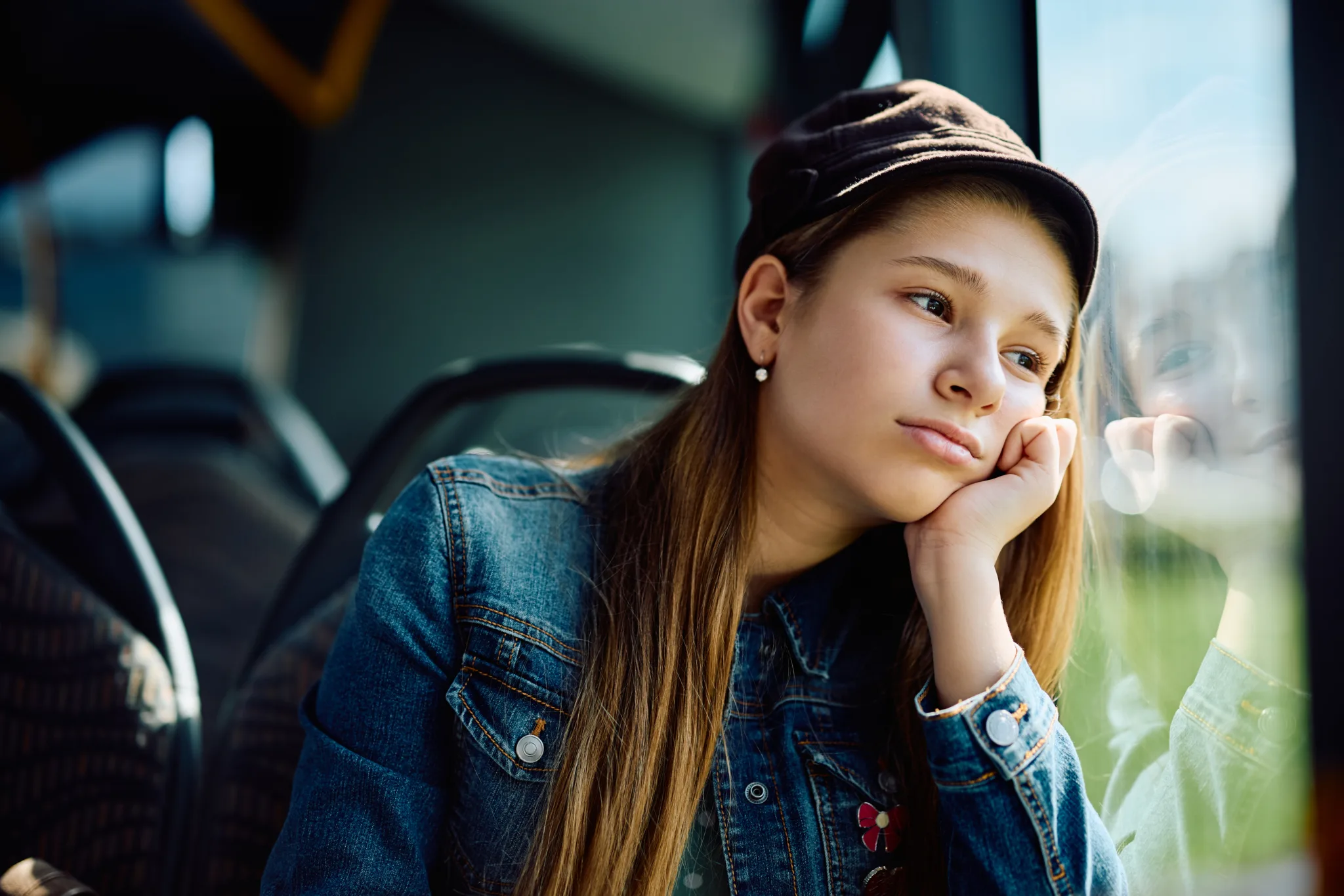 Pensive little girl feeling bored while traveling by public bus.