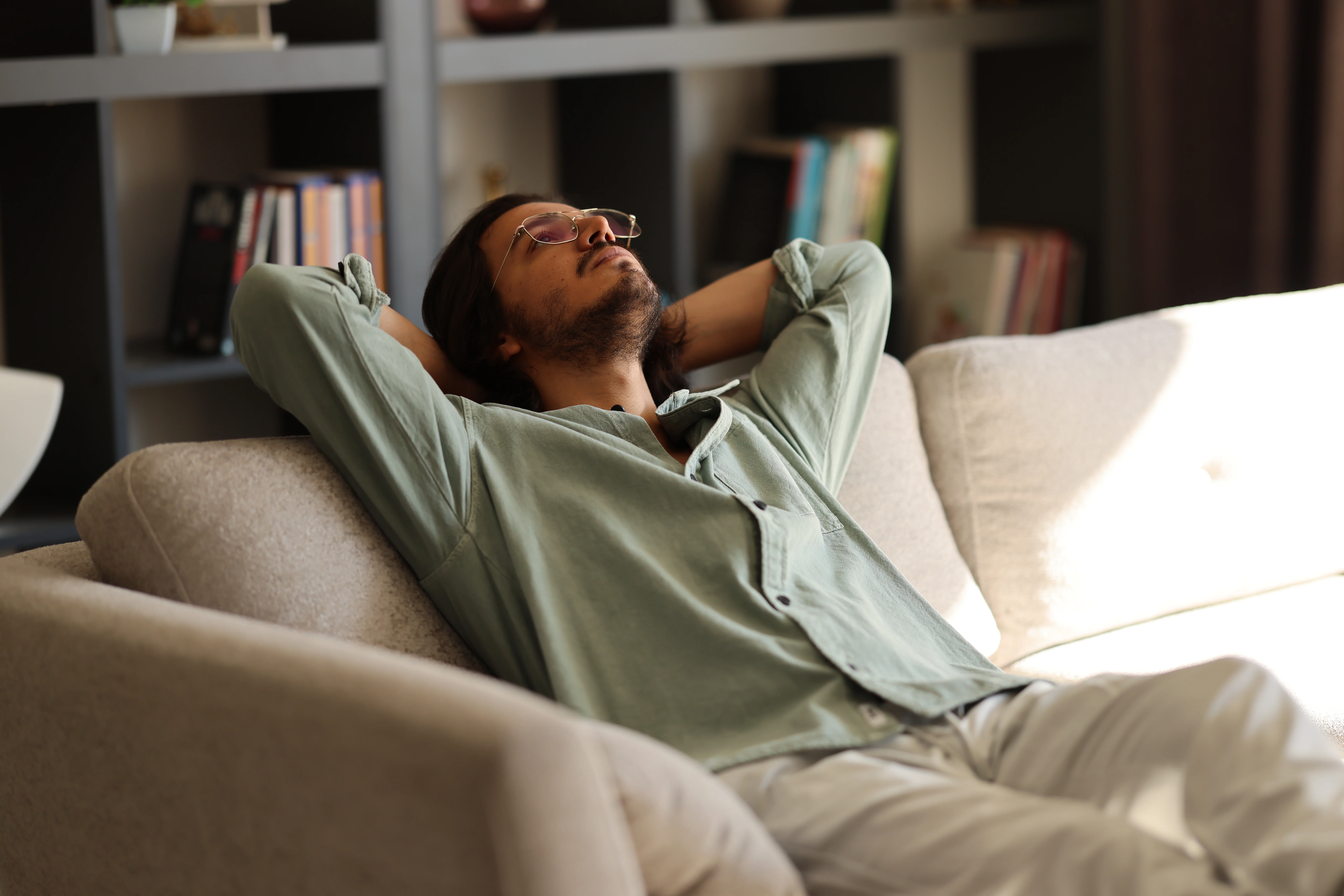Close up dreamy man looking to aside, relaxing on couch