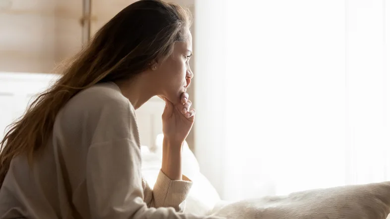 Young adult female distressed looking out a window