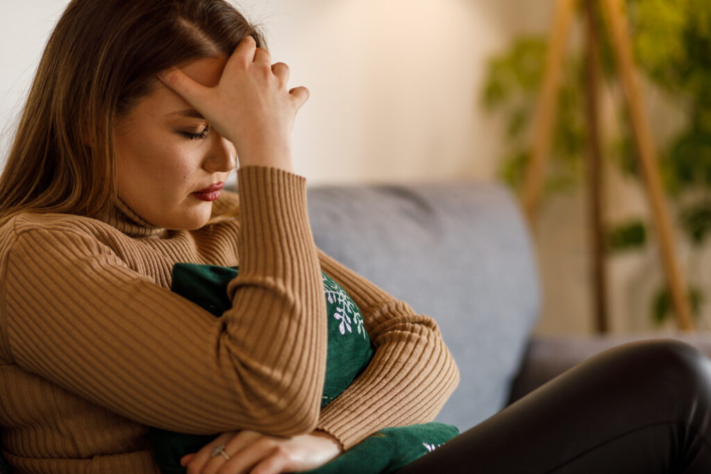 Young woman holding her head in her hand as she struggles with intrusive thoughts