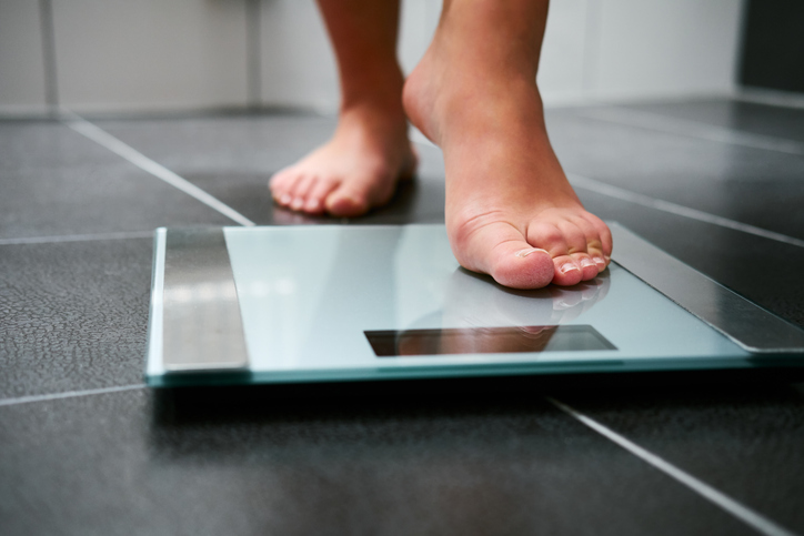adult going to step on a scale to check their weight