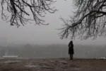 Girl standing alone in the park on gloomy day.