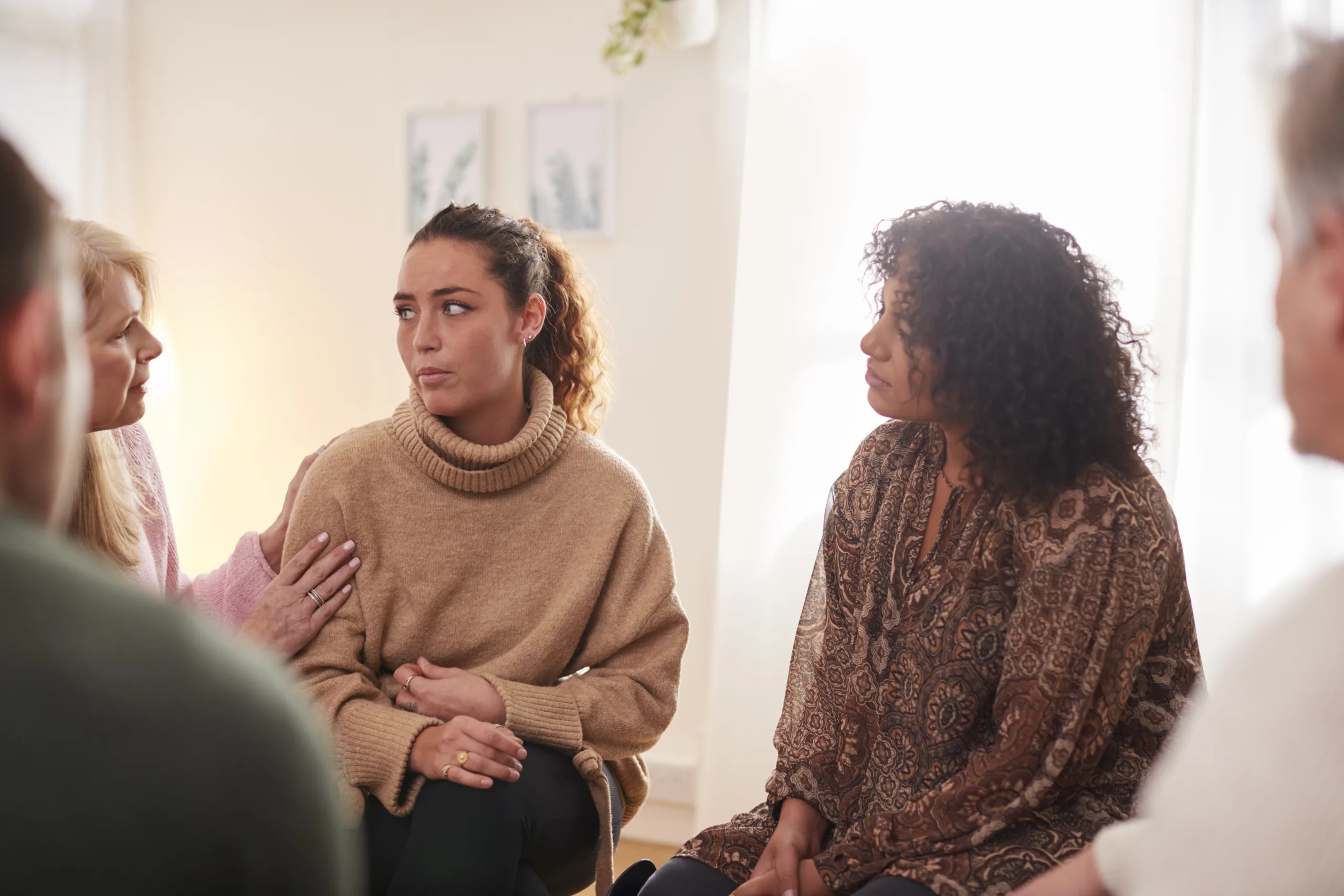 Group Consoling Woman Speaking At Support Group Meeting For Mental Health Or Dependency Issues