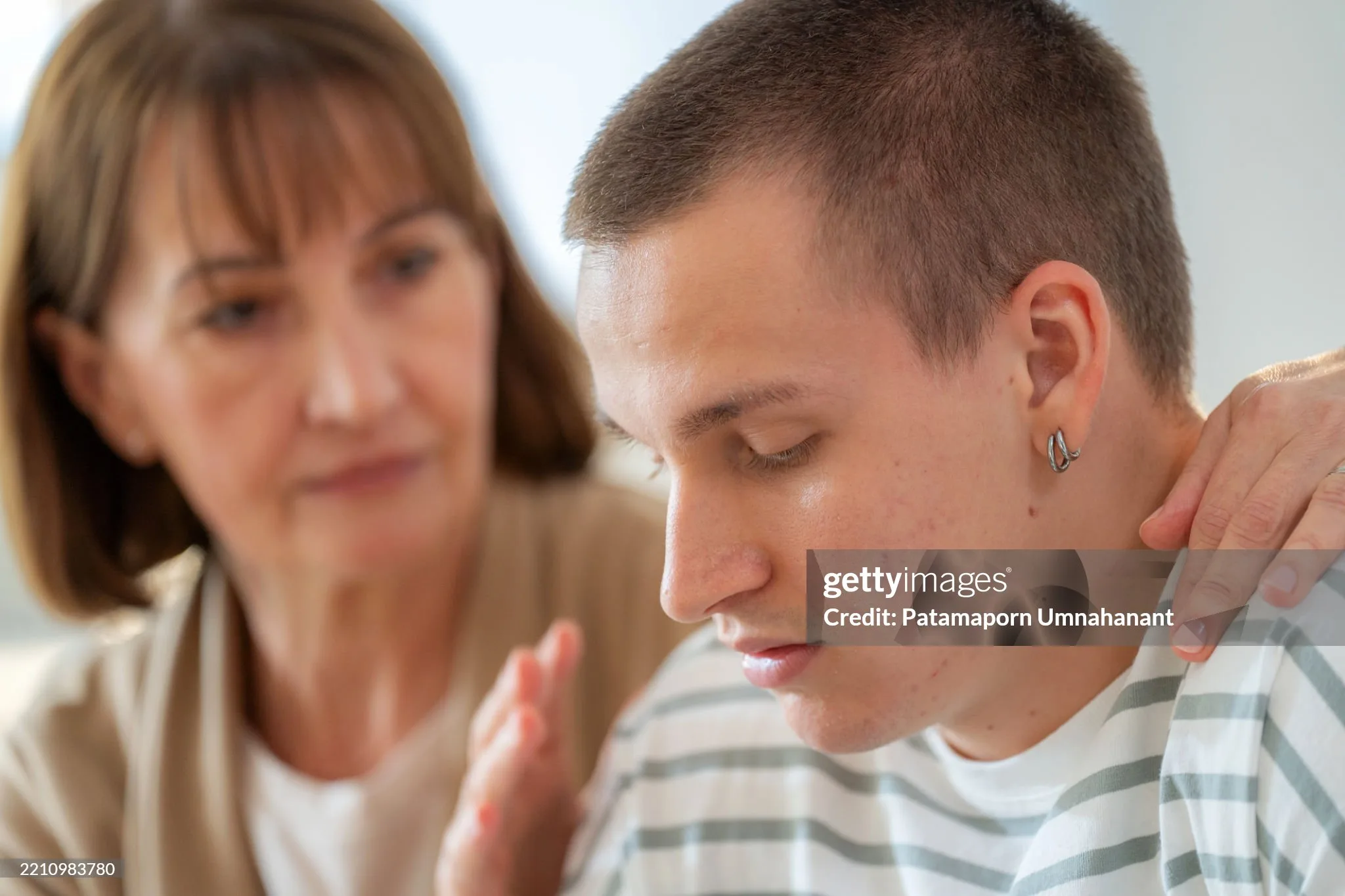 In a serious living room conversation, a teenage son argues while his concerned mother offers encouragement. This emotional family scene highlights communication challenges, love, support, and the parenting struggles of adolescence and understanding.