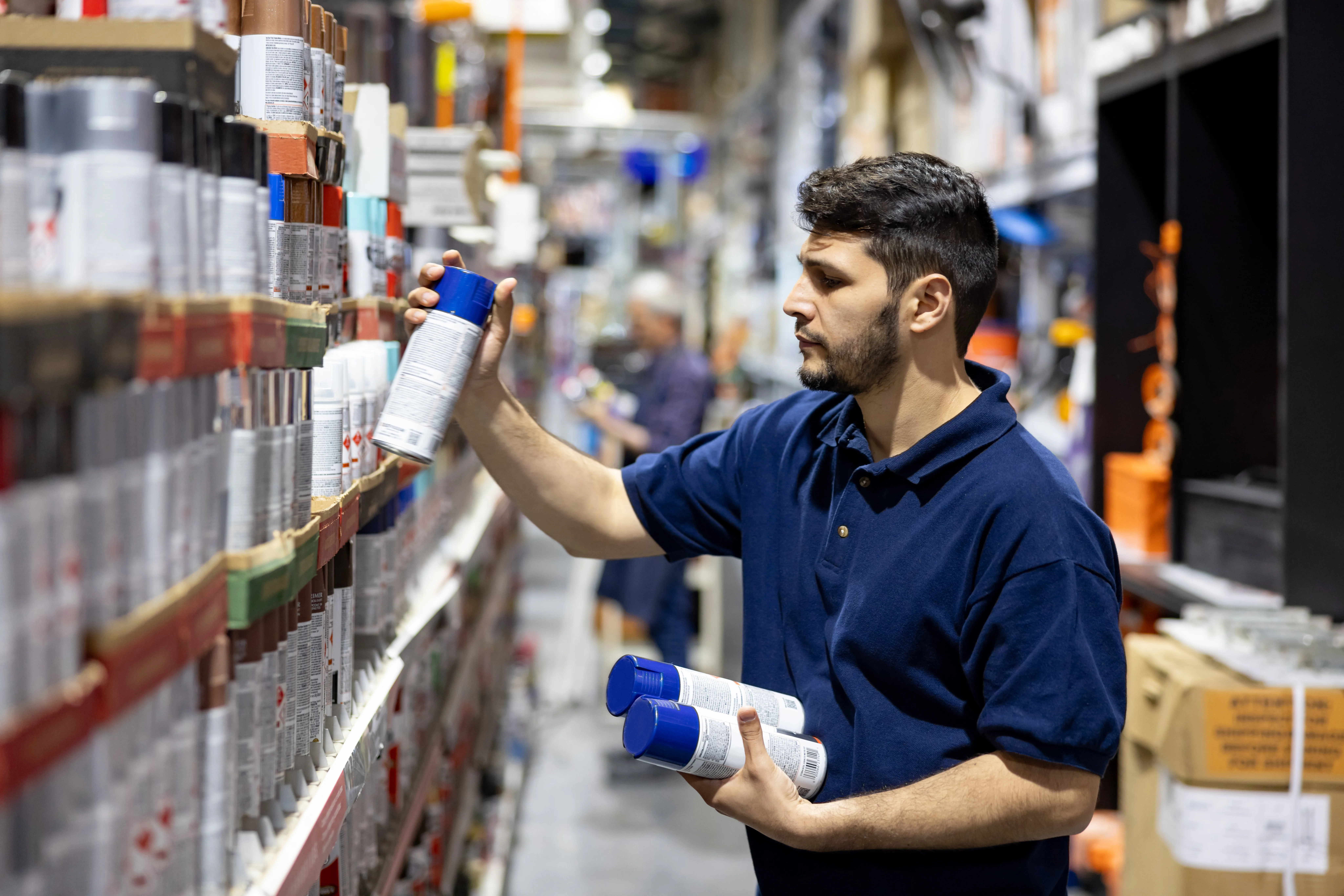 Latin American employee working at a hardware store restocking the shelves - people at work concepts