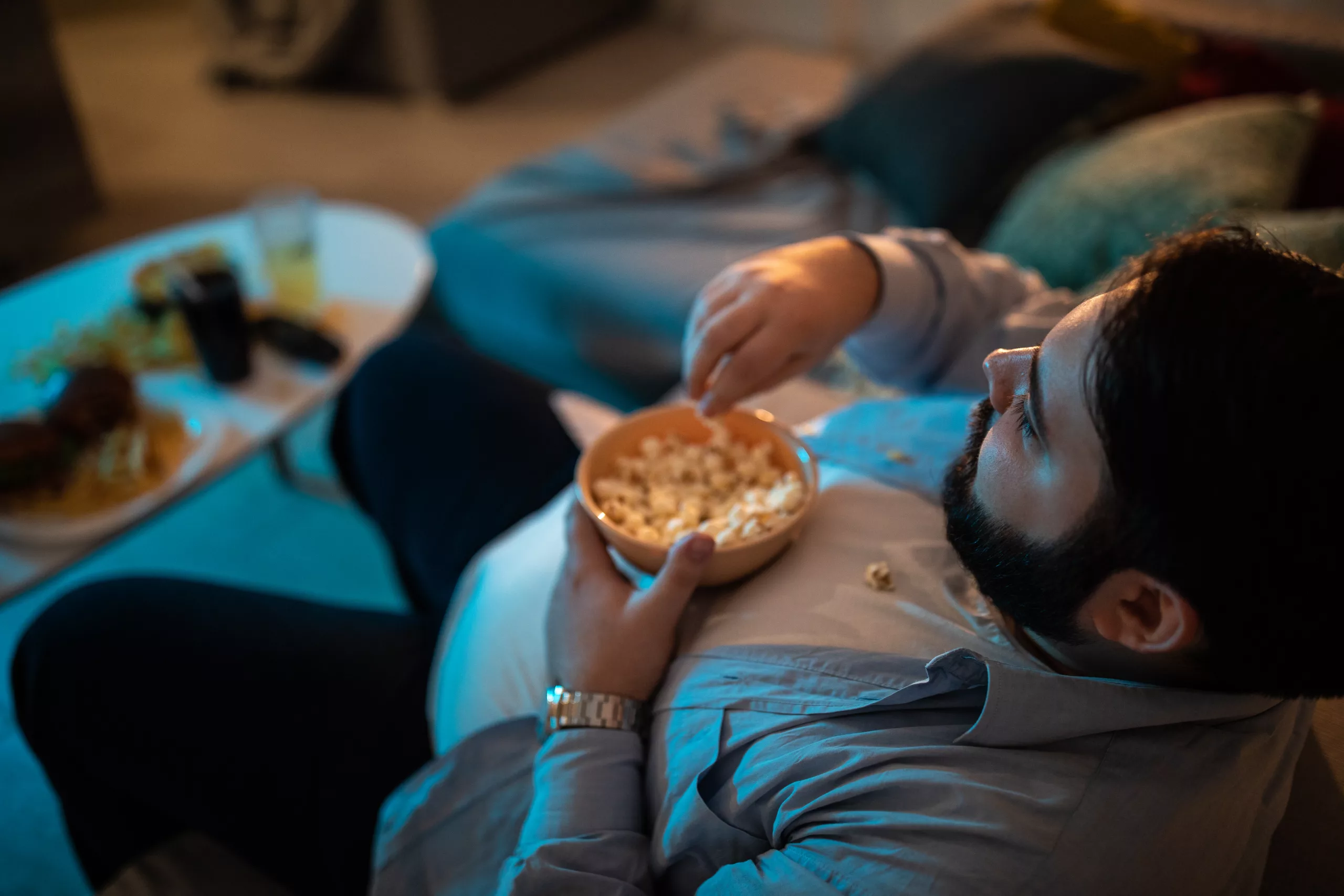 Man sitting in front of TV in living room and eating popcorn