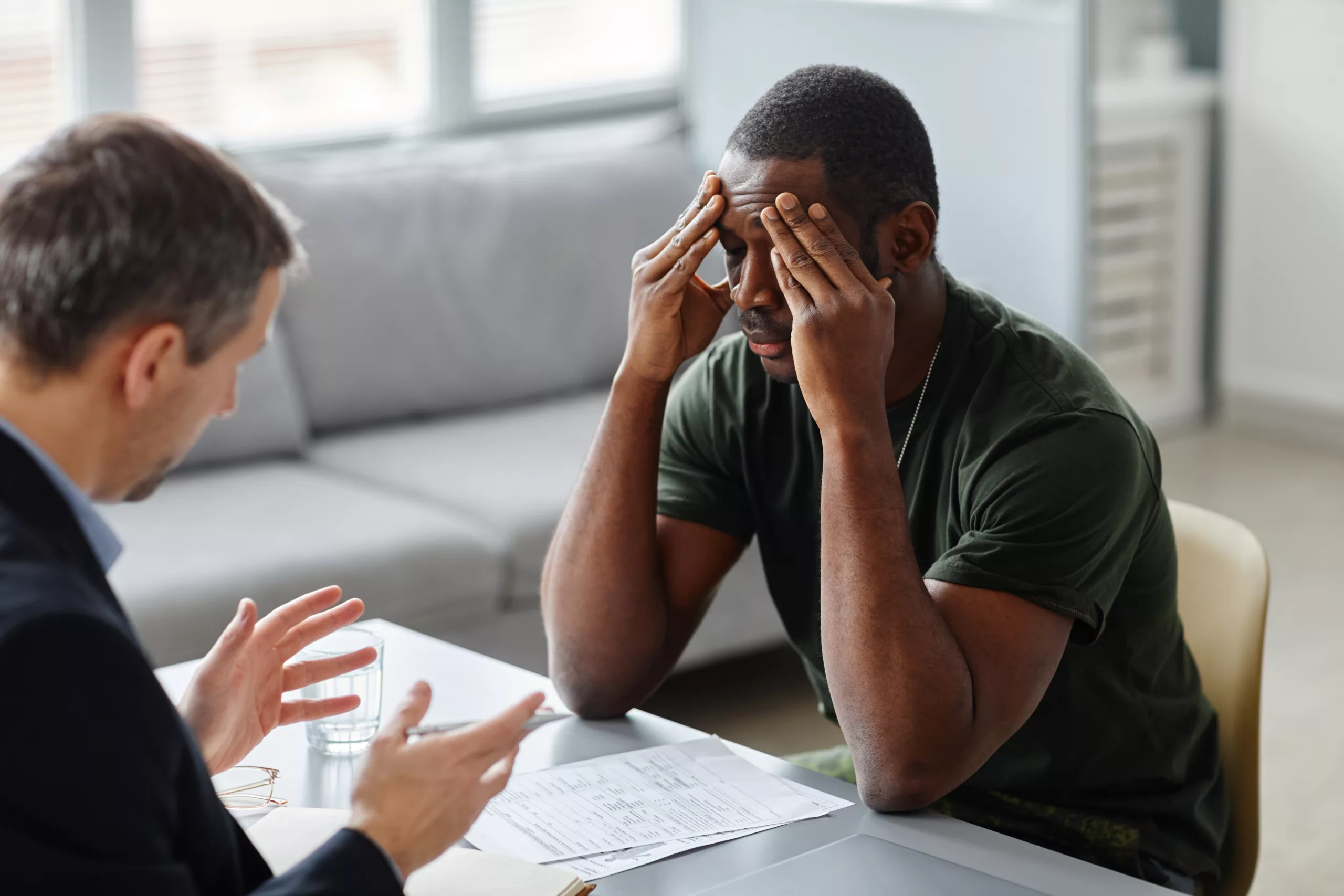 Professional psychiatrist having therapy session with young African American military man with PTSD