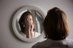 Reflection of a woman's face in broken mirror. Depression, anxiety, phobia, suicide and mental health concept.