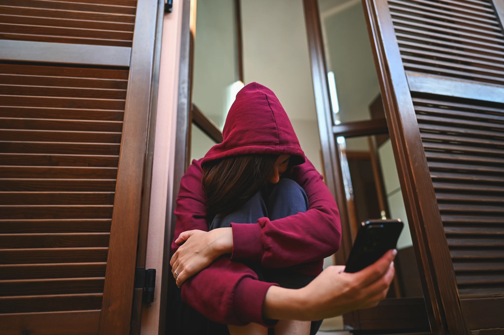 Sad young woman holding smartphone and feeling desperate at home